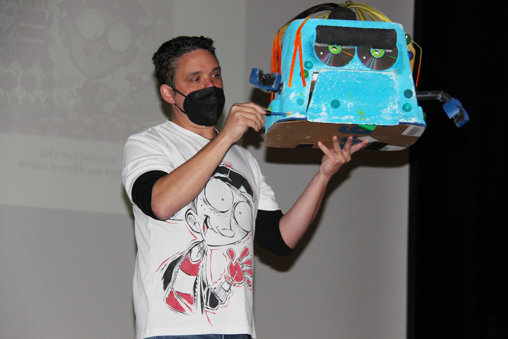 Author Daniel Jude Miller holding a craft robot, presenting 
