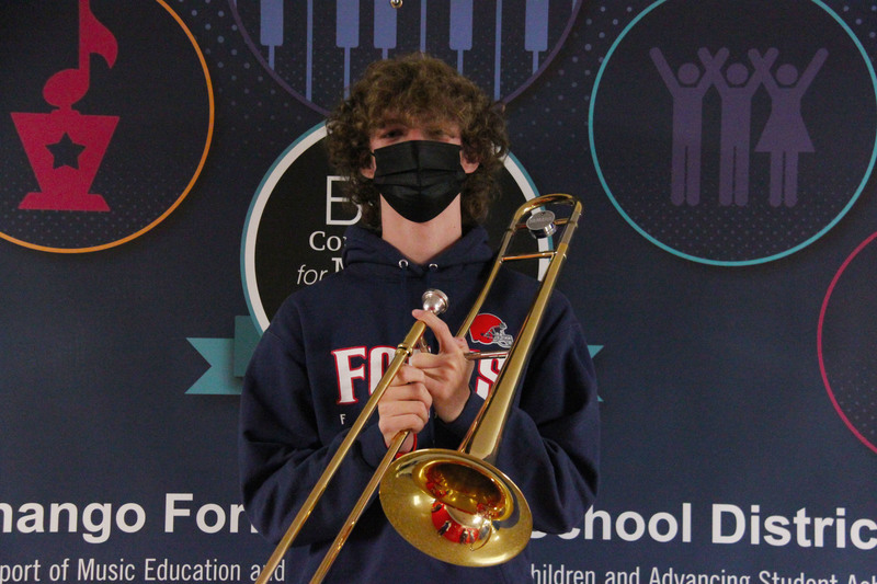 student Maddox Thornton holding brass trombone and posing for picture